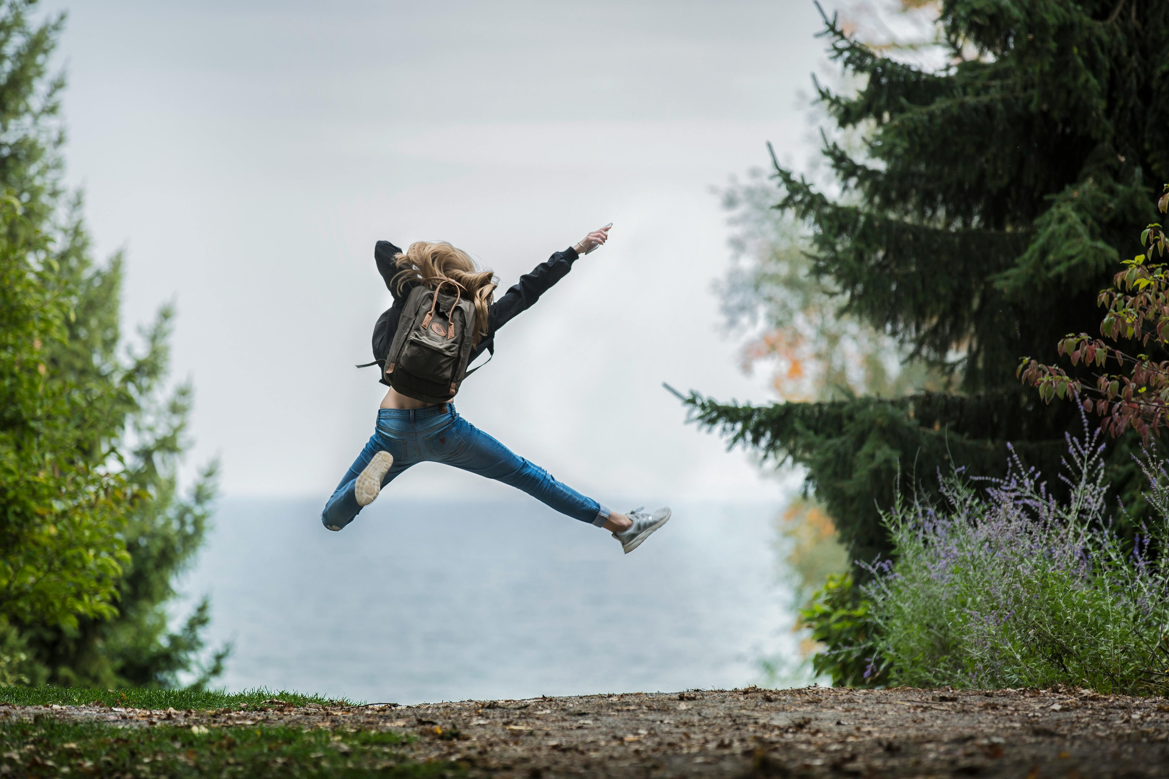 A backpacking girl jumps in nature